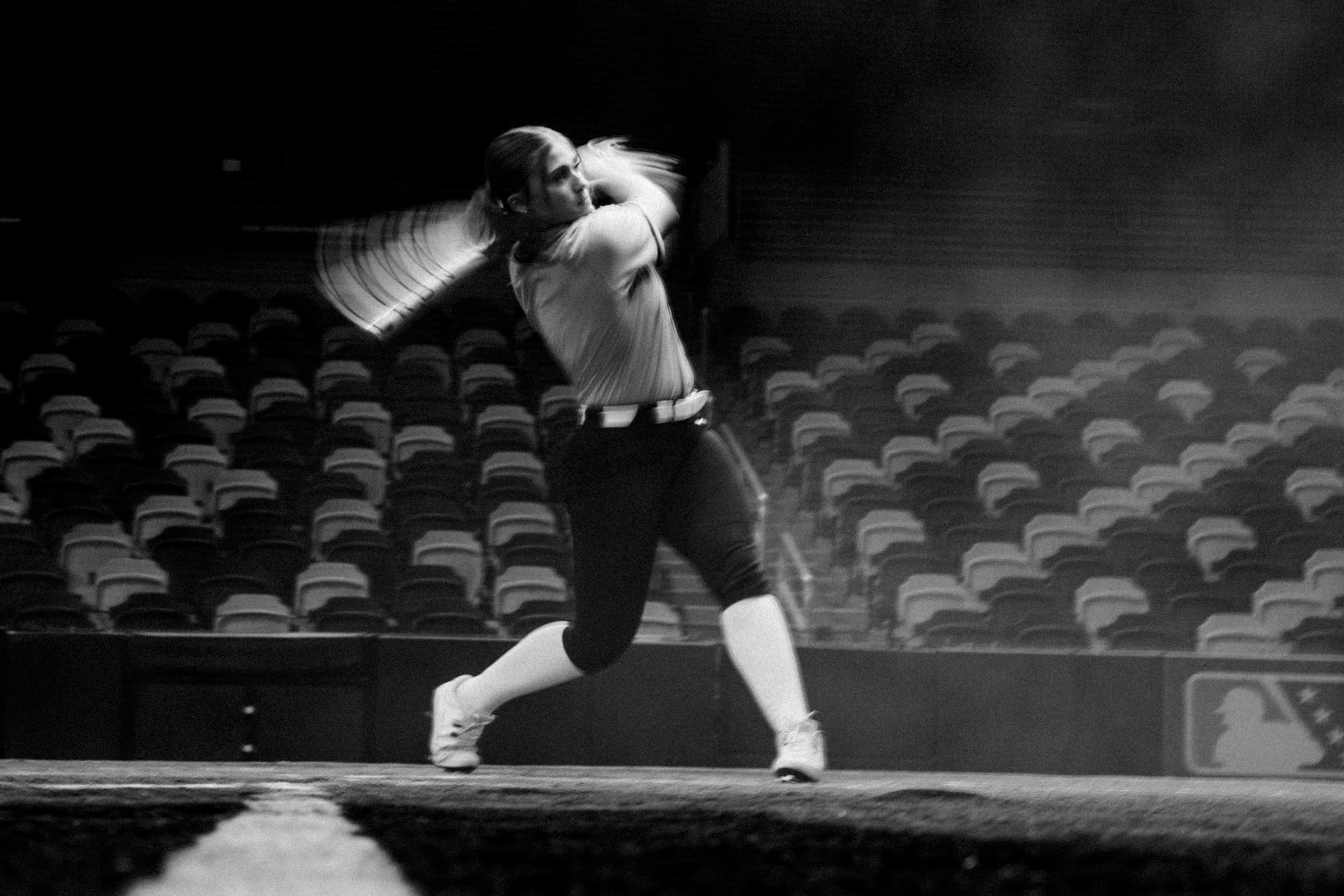 A batter at the plate in an empty stadium, bat blurred through the swing.